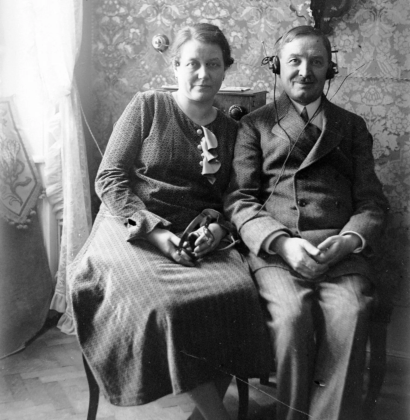 A man and a woman seated side by side; he wears a headset, she holds one in her lap