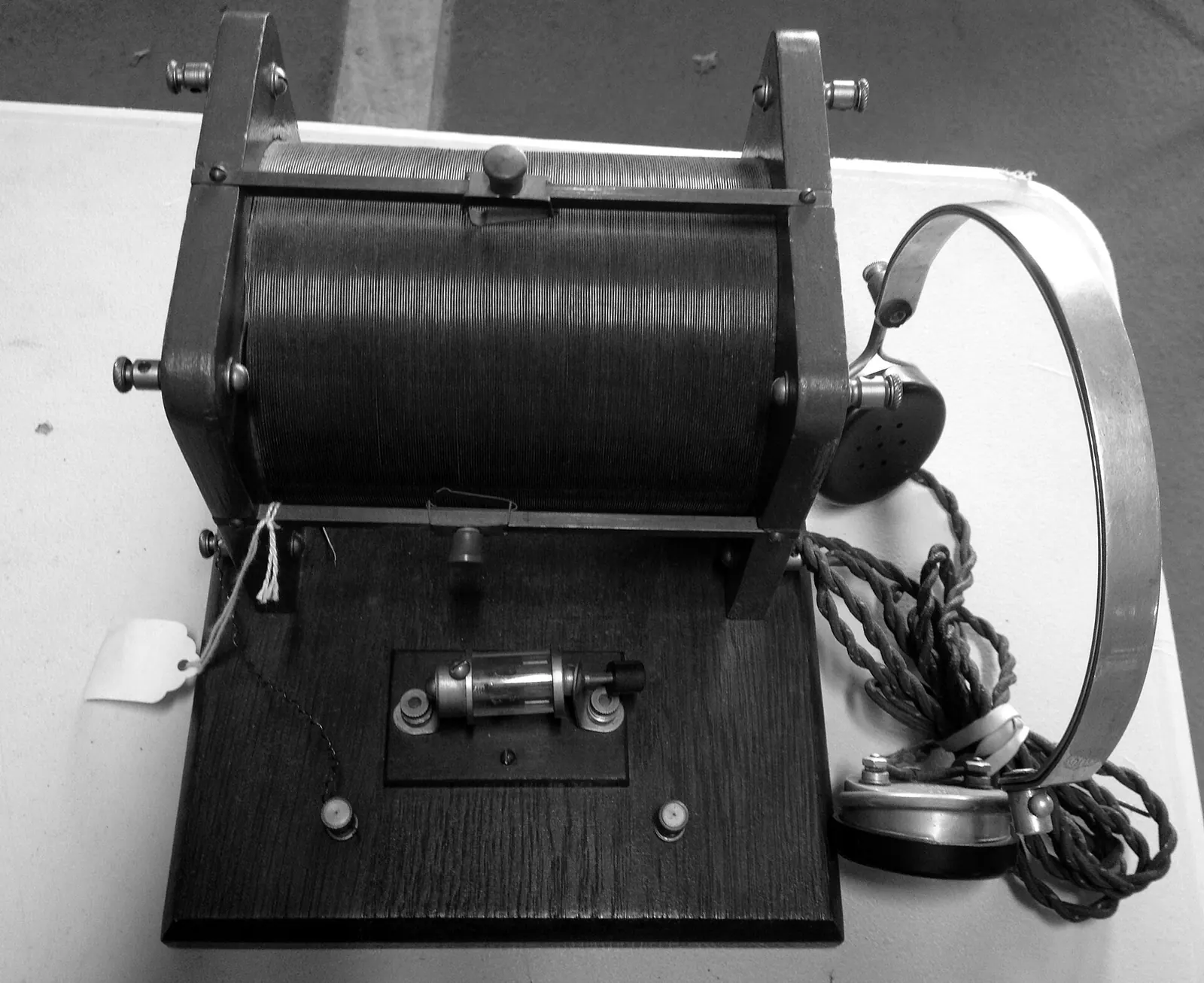 A crystal radio set with a copper coil on a wooden base and a pair of early headphones beside it